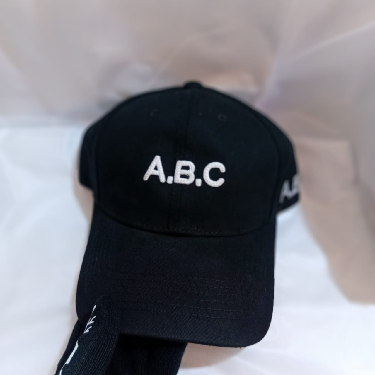 Black cap with A.B.C embroidery on front and side.