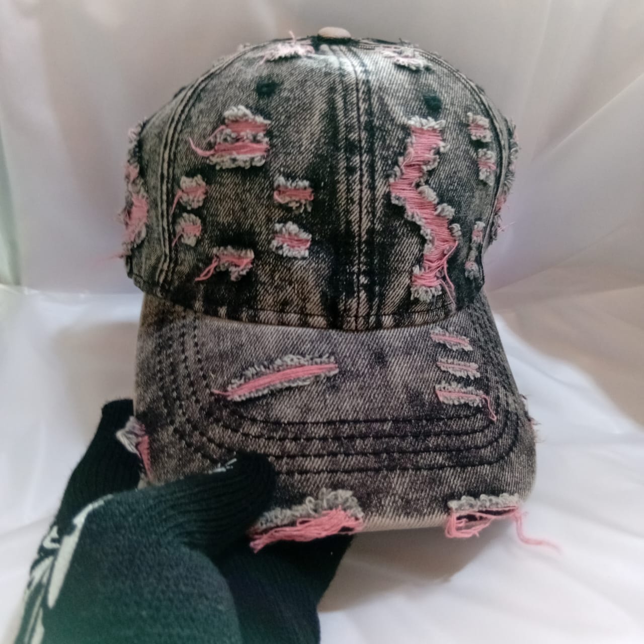Distressed gray denim cap with pink thread repairs and rips.