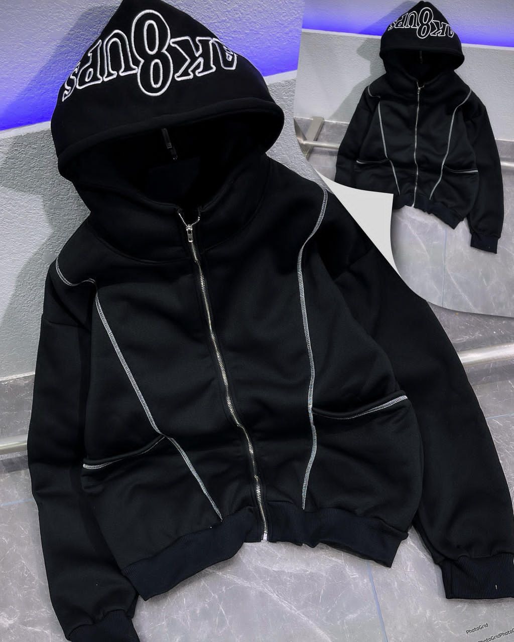 Black zip-up hoodie with white embroidered hood and contrast stitching.