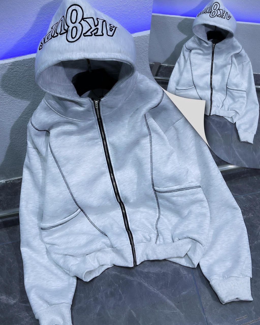 Light gray zip-up hoodie with embroidered hood detail and contrast stitching.