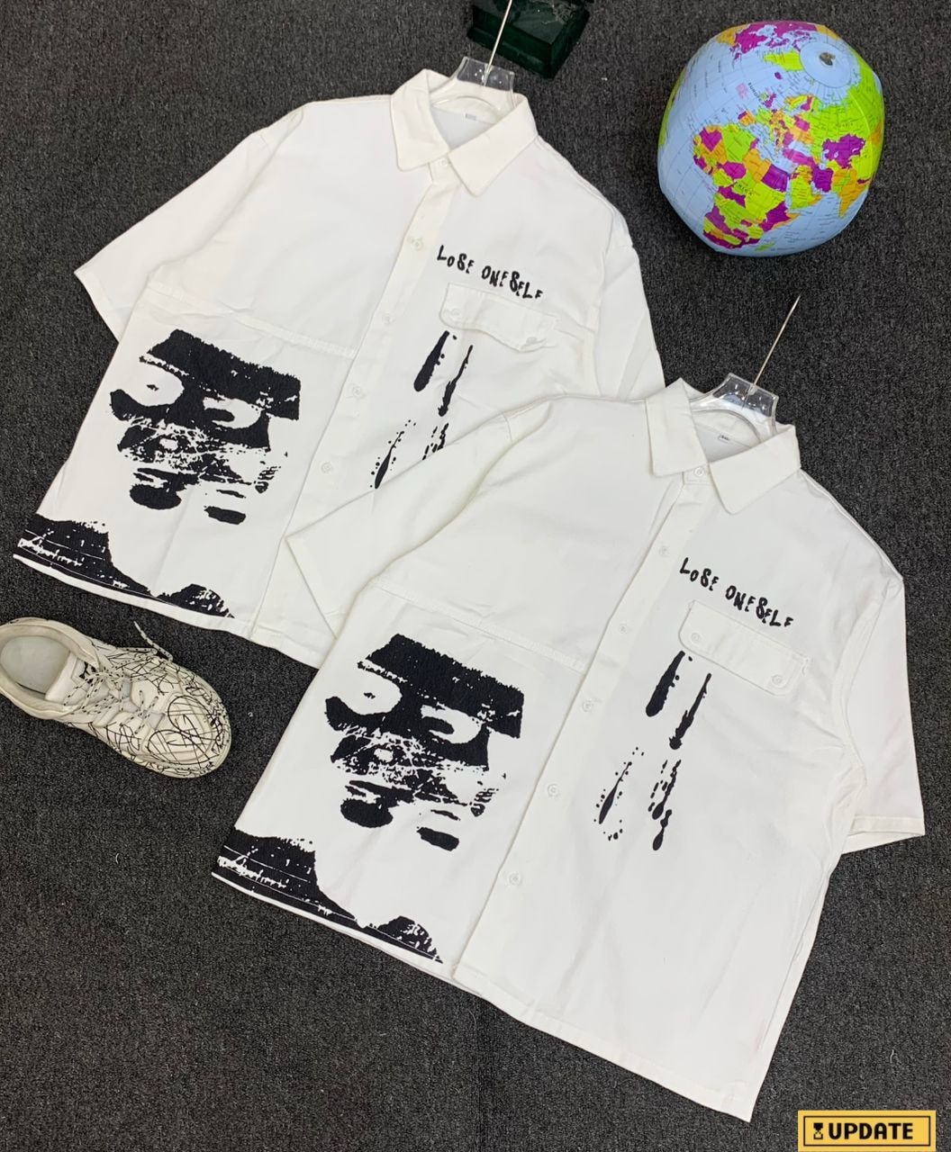 Two white short sleeve shirts with black face graphic and LOVE ONESELF text.