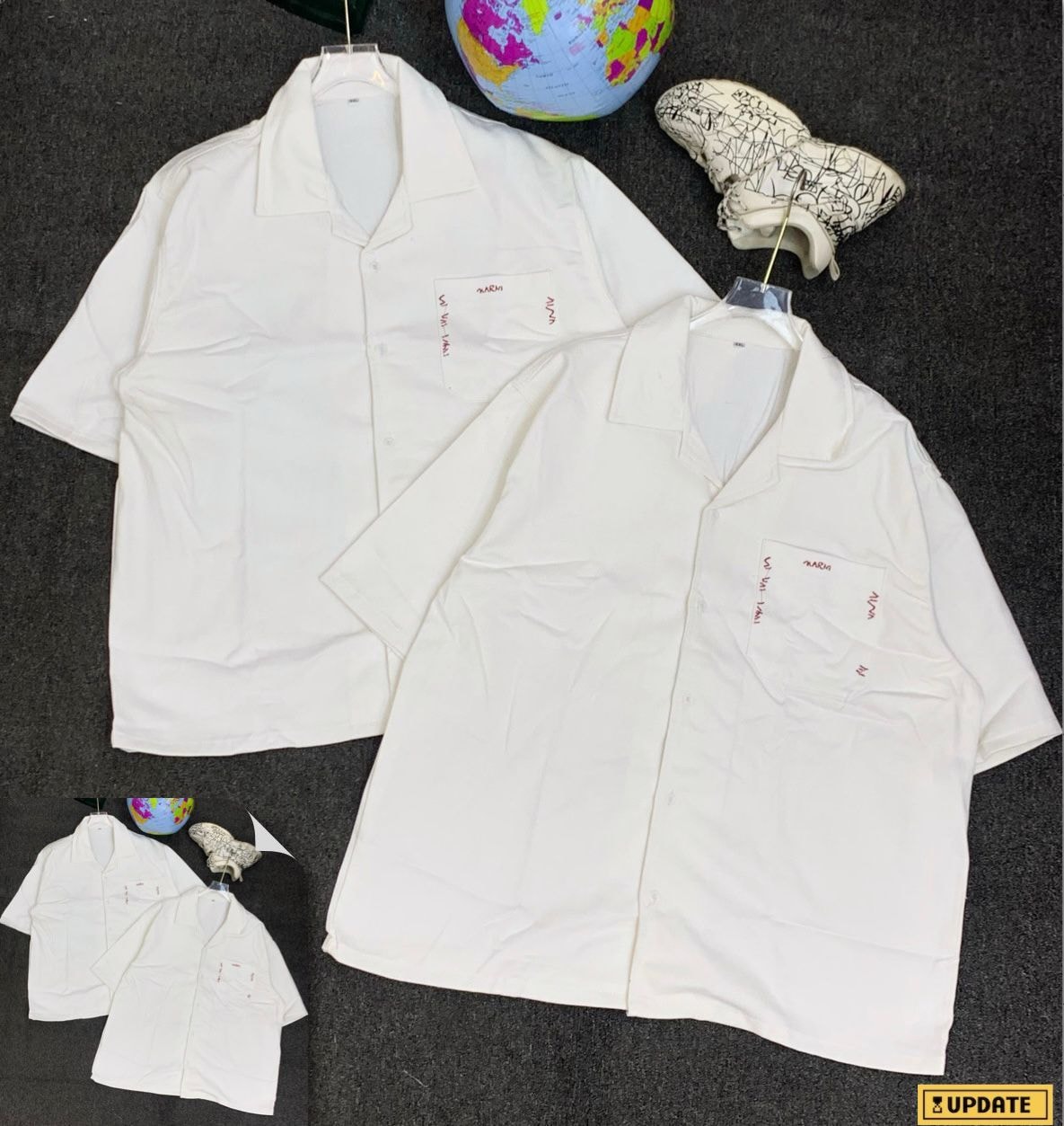 Two white short sleeve shirts with red embroidery on chest pocket.