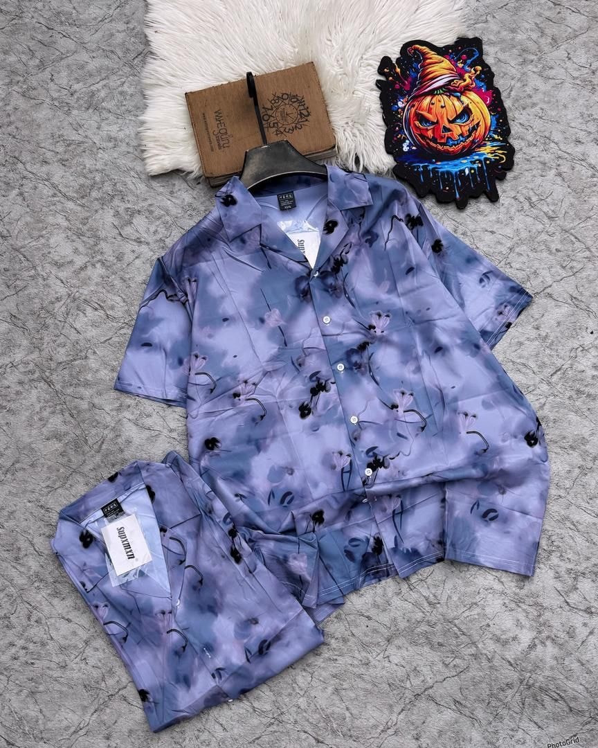 Purple abstract floral short sleeve shirt and matching shorts laid flat with props.