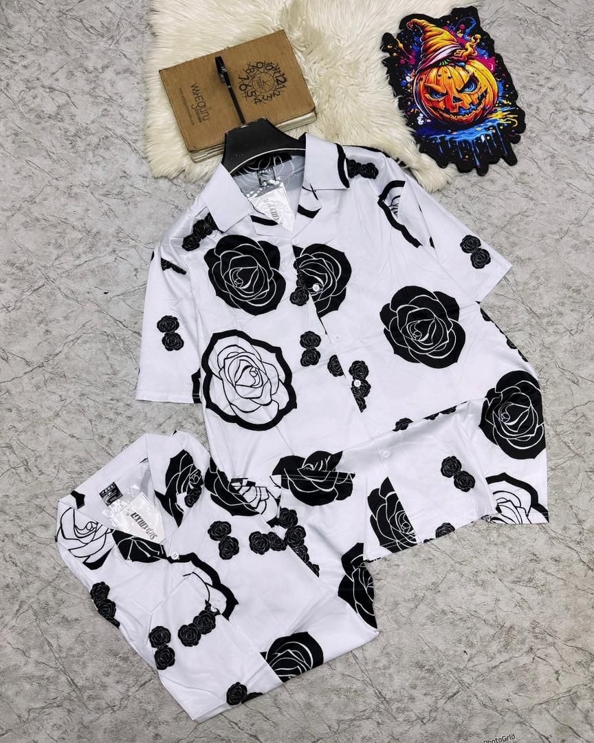 White short sleeve shirt and shorts with black rose prints laid flat with props.