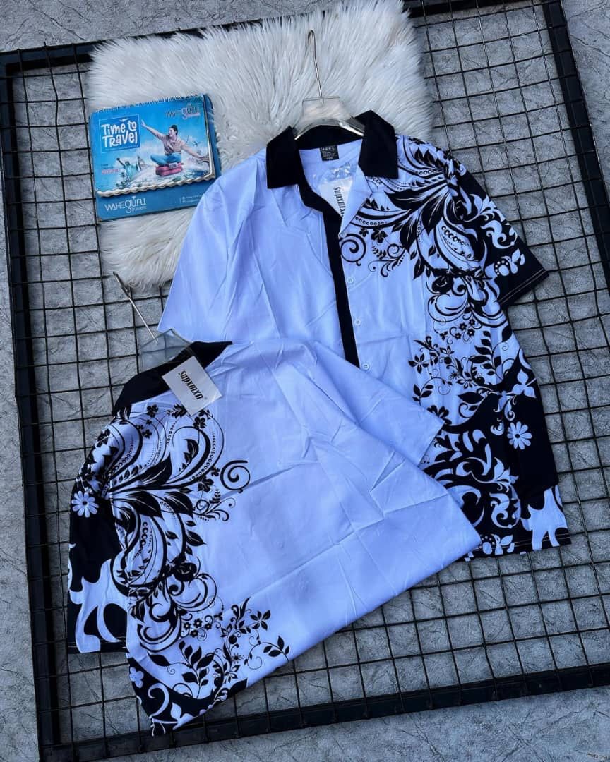 Light blue short sleeve shirt with black paisley print and matching shorts laid flat.