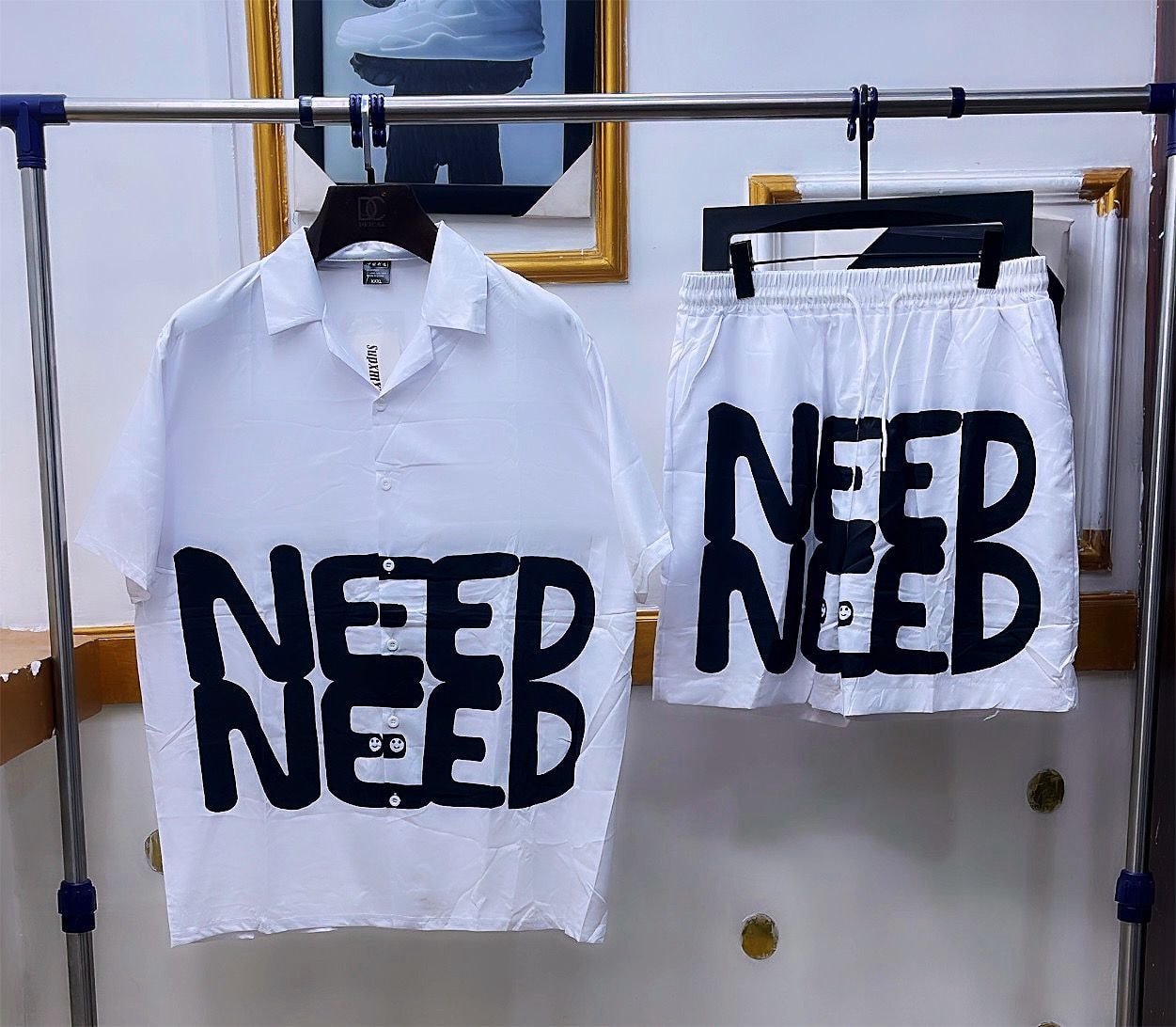 White shirt and shorts set with large black NEED text graphic.