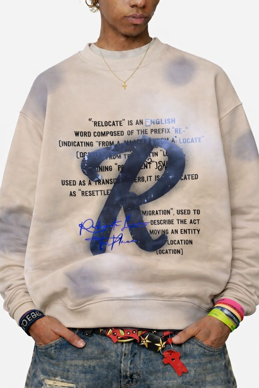 Model wearing cream bleached relocate graphic sweatshirt with text and signature print.
