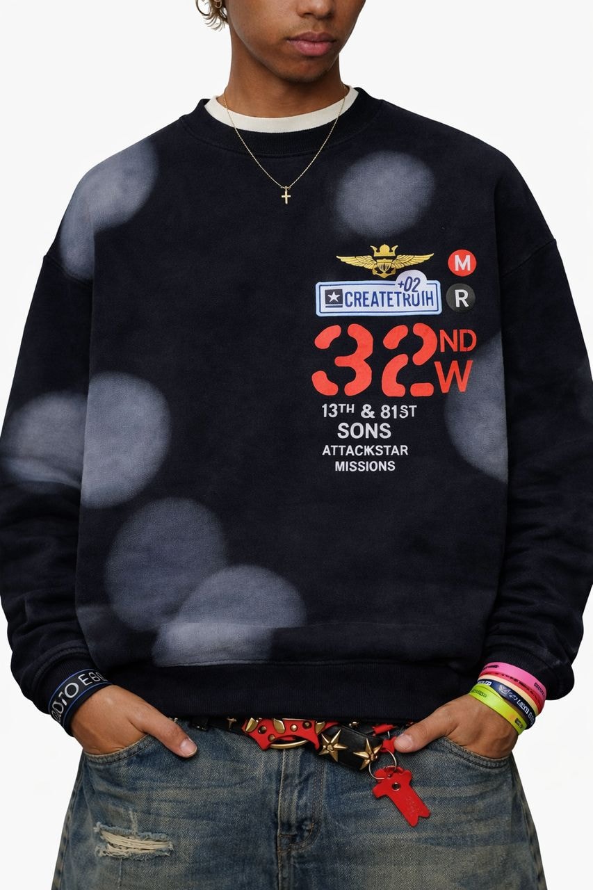 Model wearing black bleached 32ND W graphic sweatshirt with red and blue details.