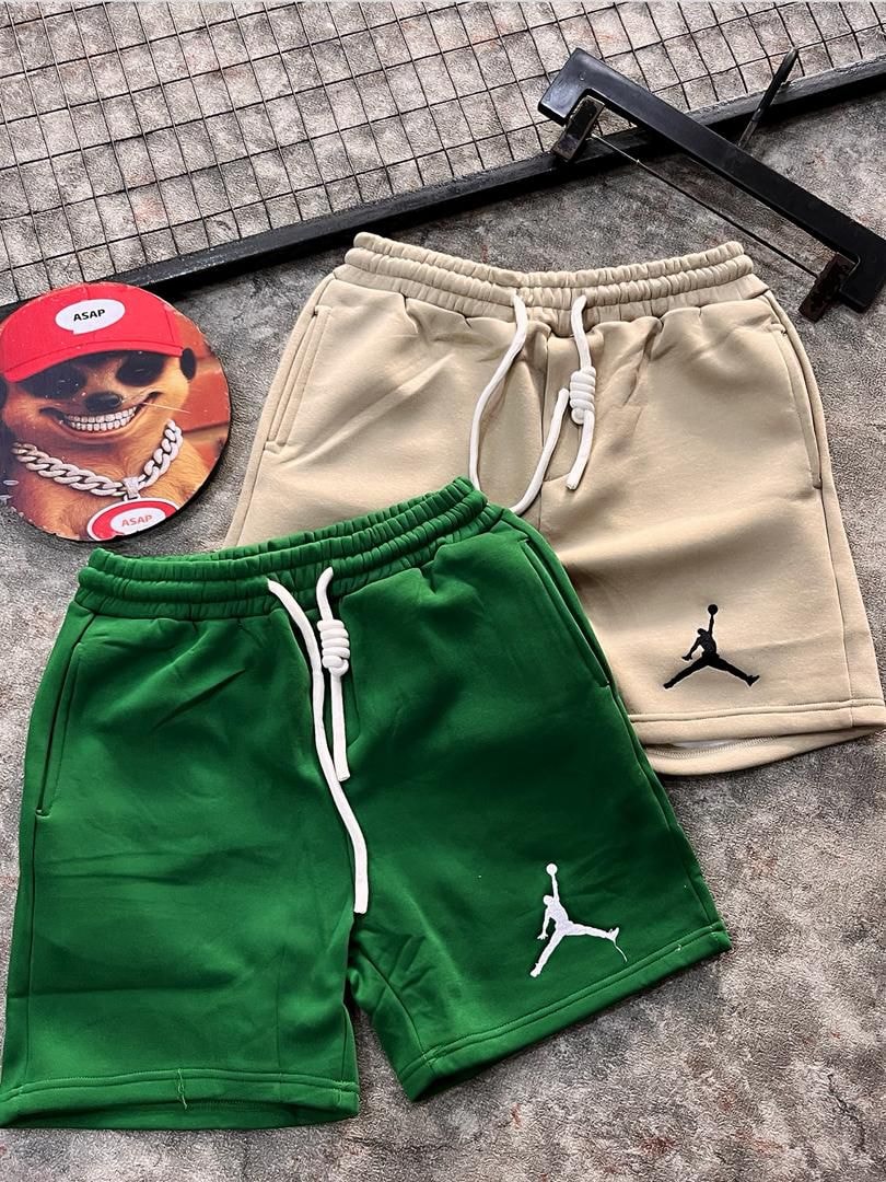 Beige and green jogger shorts with elastic waistbands and white drawcords.