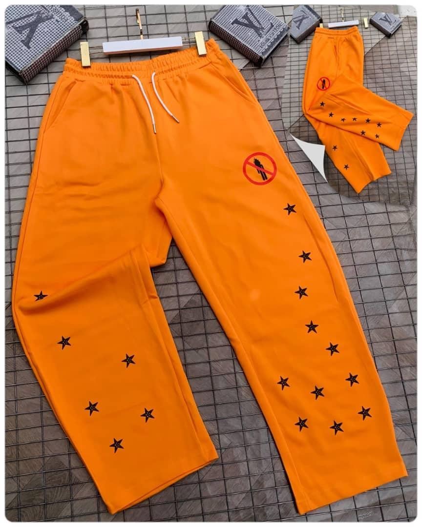 Orange joggers with black star embroidery and red graphic patch on thigh.
