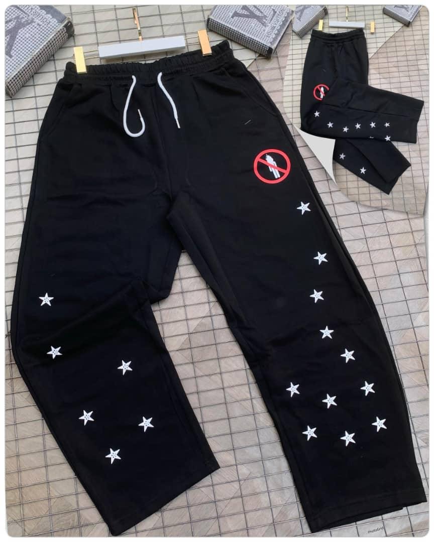 Black joggers with white star embroidery and red graphic patch on thigh.