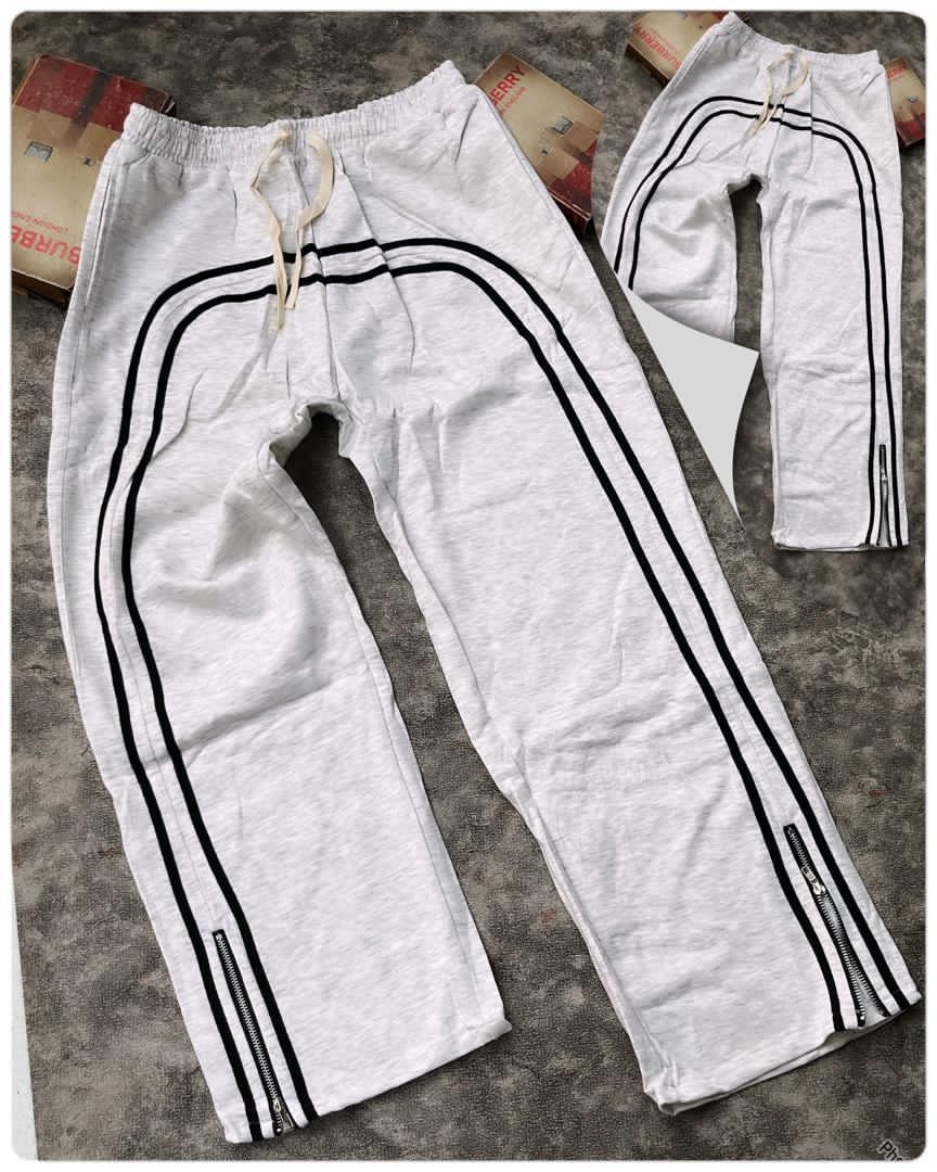 White curved stripe joggers in flat lay showing zip details.