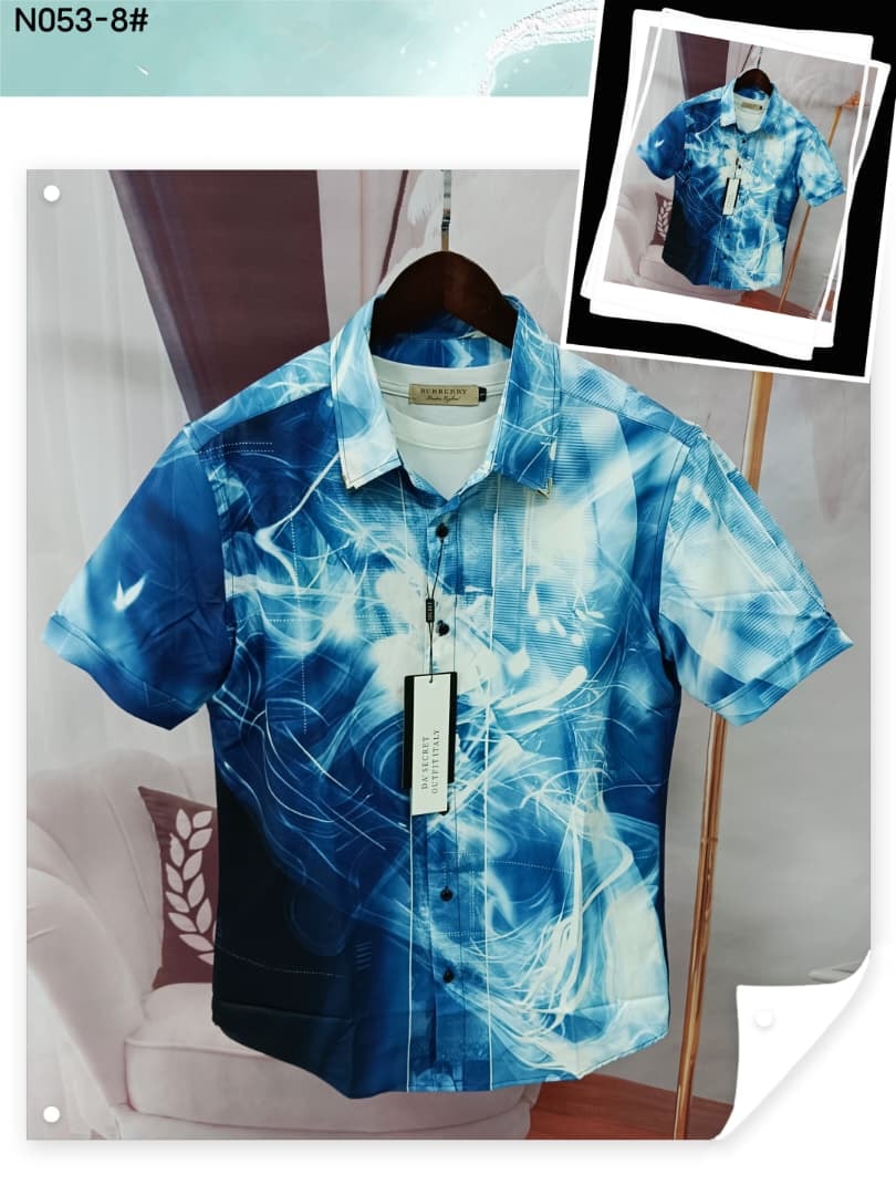 Short sleeve shirt with blue and white abstract swirl print on hanger.