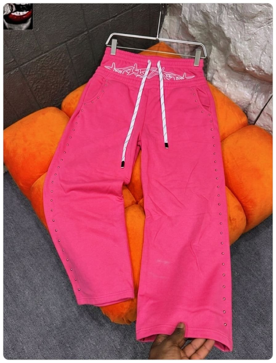 Pink studded joggers with white embroidered waistband graphic.