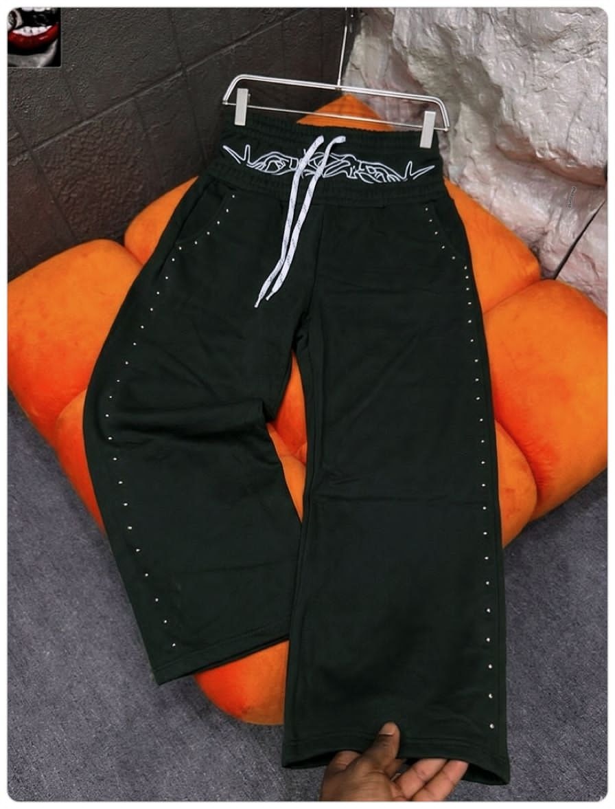 Black studded joggers with white embroidered waistband graphic.