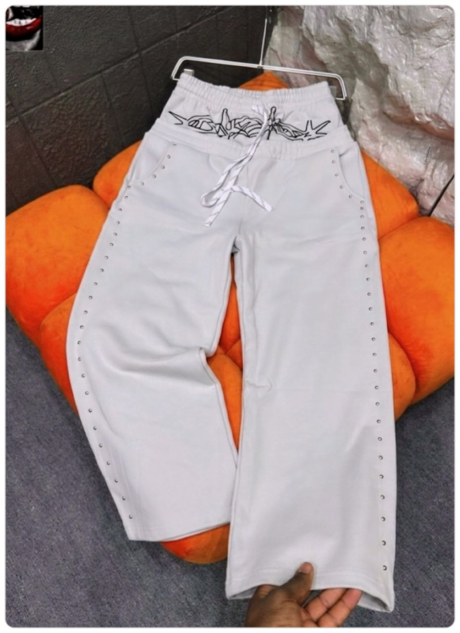 White studded joggers with black embroidered waistband graphic.