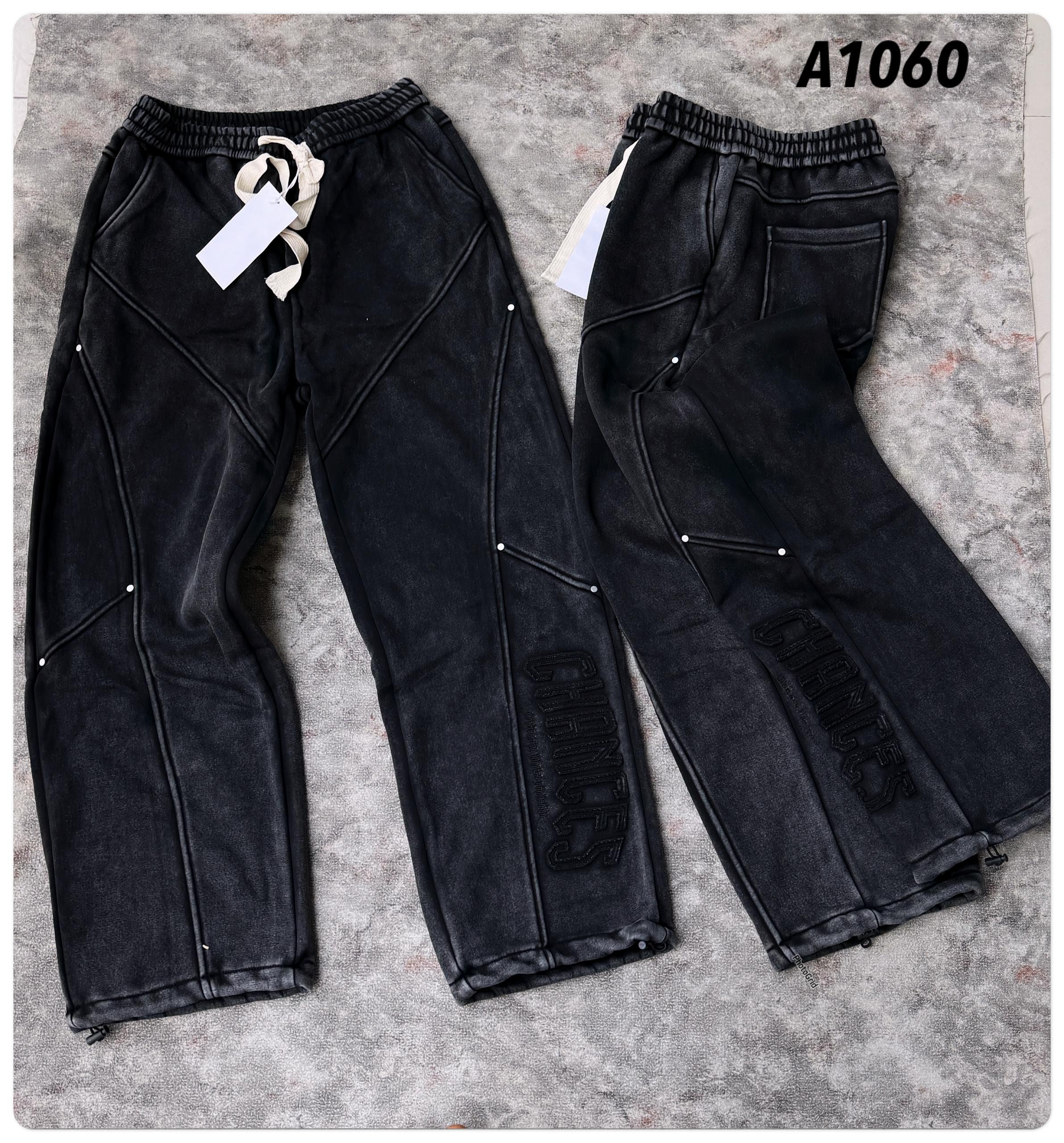 Overhead flat lay of black joggers showing front and back views with seam details and 'CHANCES' embroidery.