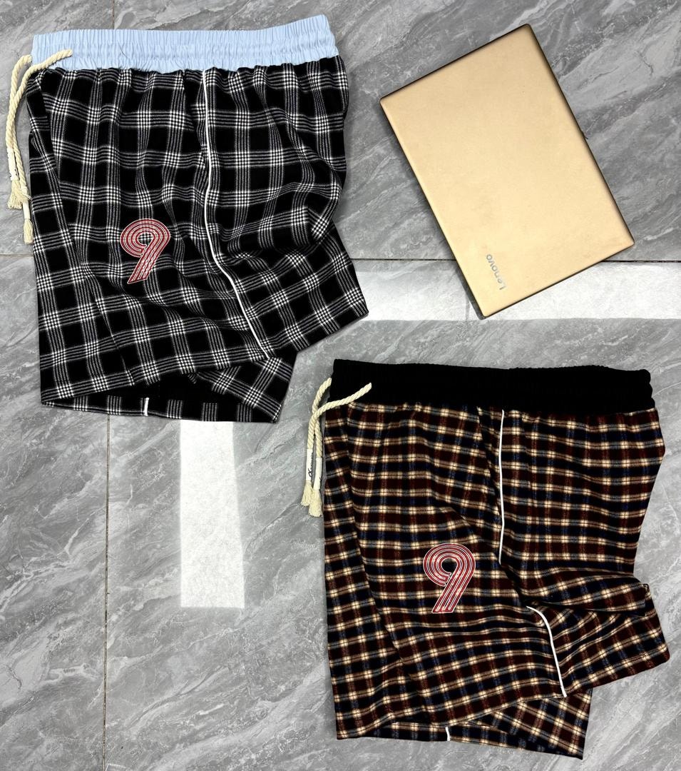 Black and white plaid shorts with light blue waist and 9 embroidery above multi brown plaid pair.