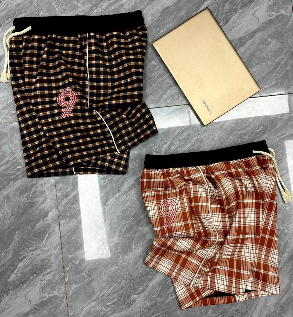 Dark brown plaid shorts with number 9 above reddish brown plaid pair on tiled surface.