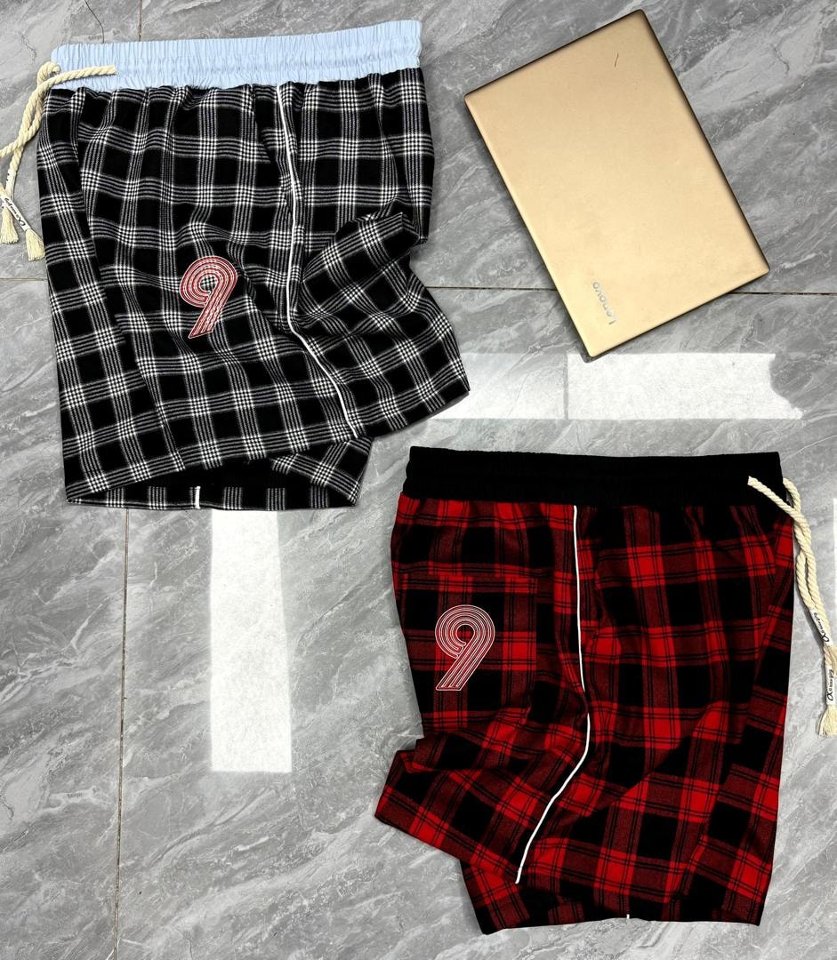 Black and white plaid shorts with embroidered 9 and light blue waistband next to red plaid version.