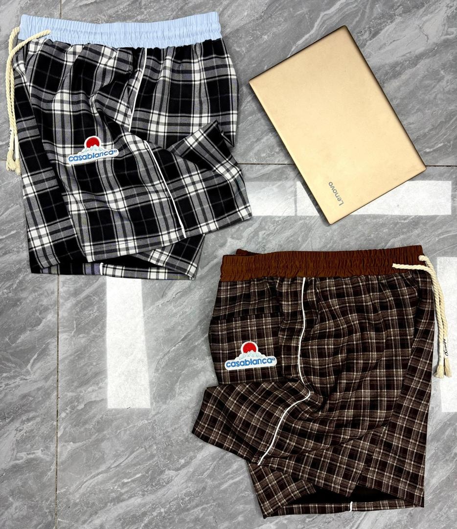 Black and white plaid Casablanca shorts with light blue waistband above brown plaid version.