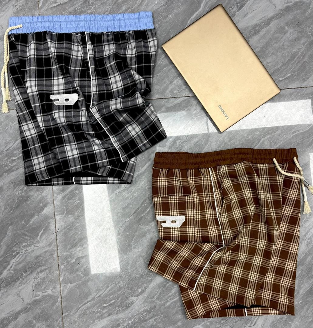 Black and grey plaid shorts with blue waistband and white emblem next to brown plaid shorts with brown waistband.