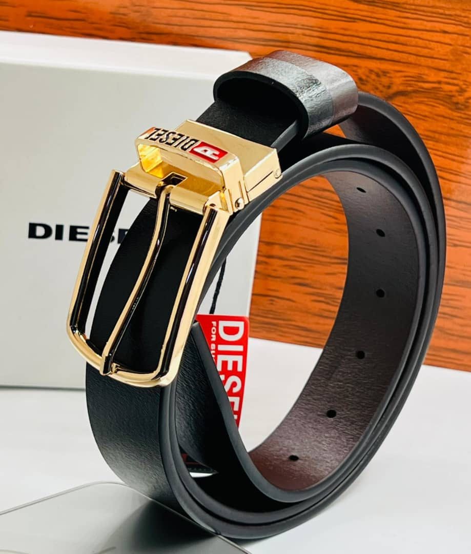 Black leather Diesel belt with prominent gold buckle and logo, displayed with white branded box.