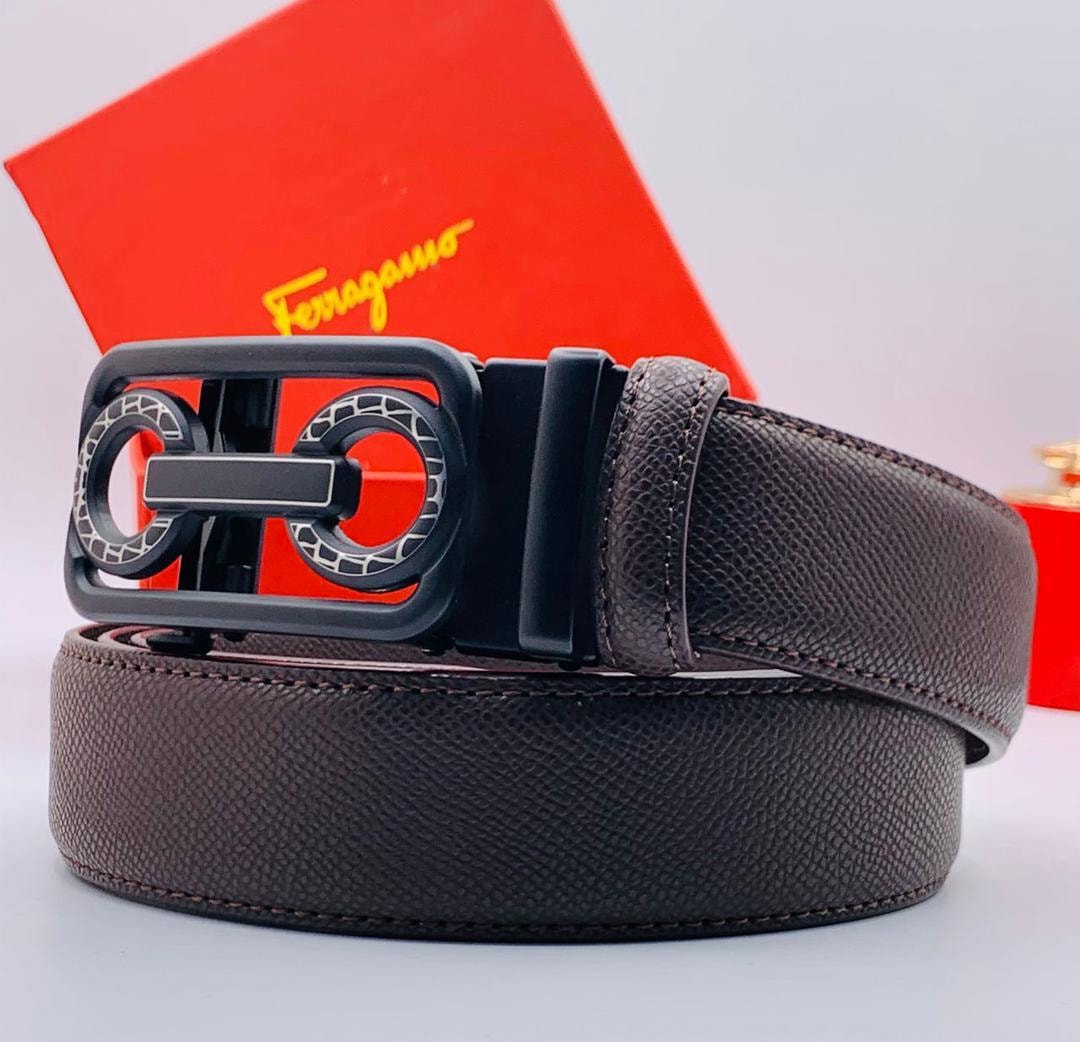 Brown pebbled leather Ferragamo belt with black and silver buckle against red branded box.