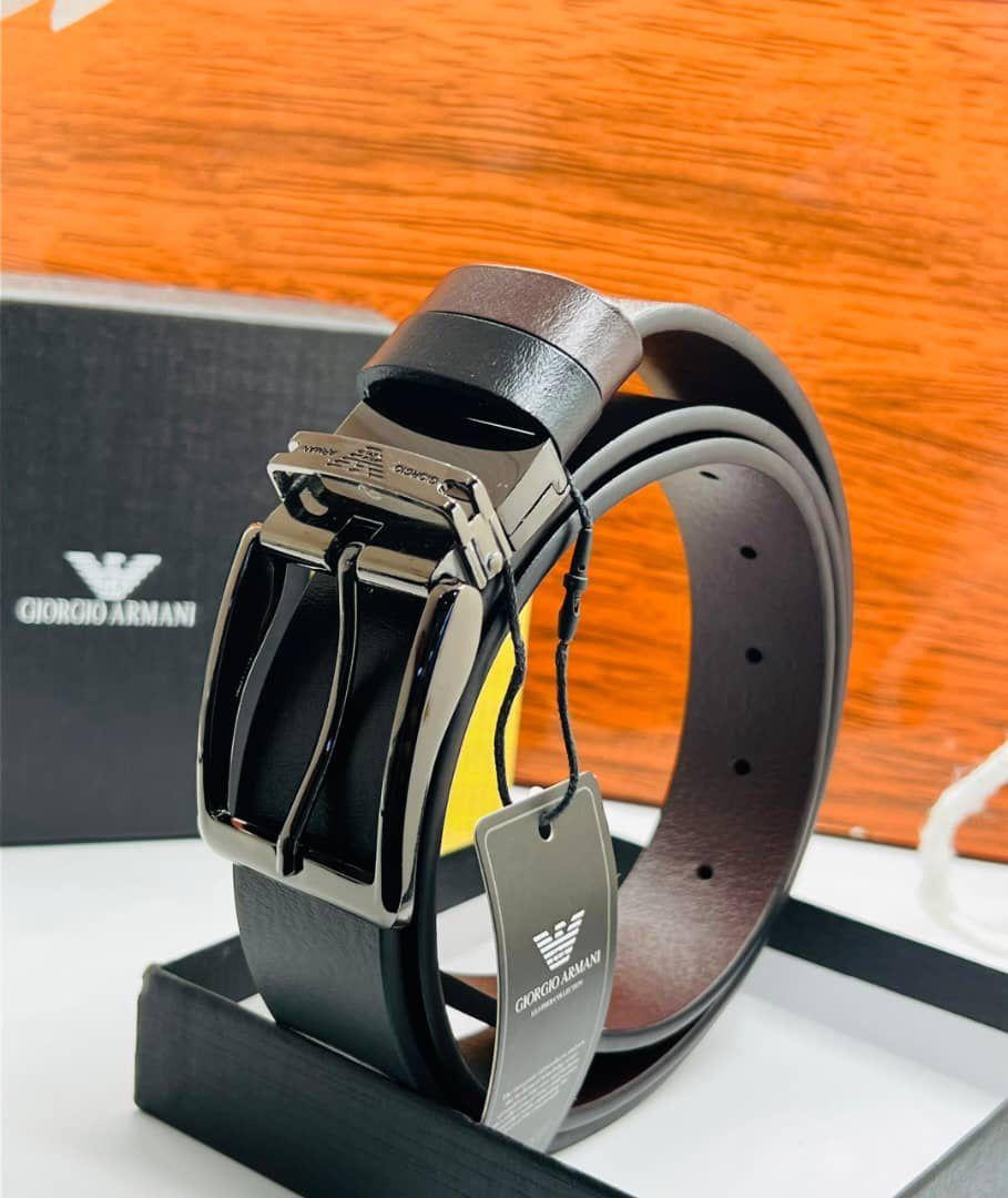 Black leather Giorgio Armani belt with silver buckle displayed on stand beside branded orange box and black packaging.