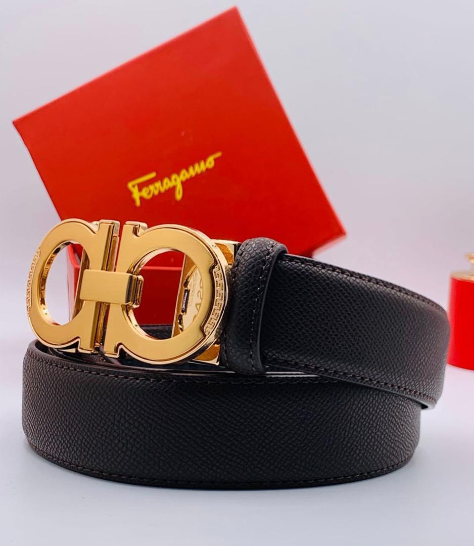 Black pebbled leather Ferragamo belt with prominent gold Gancini buckle and red branded box in background.