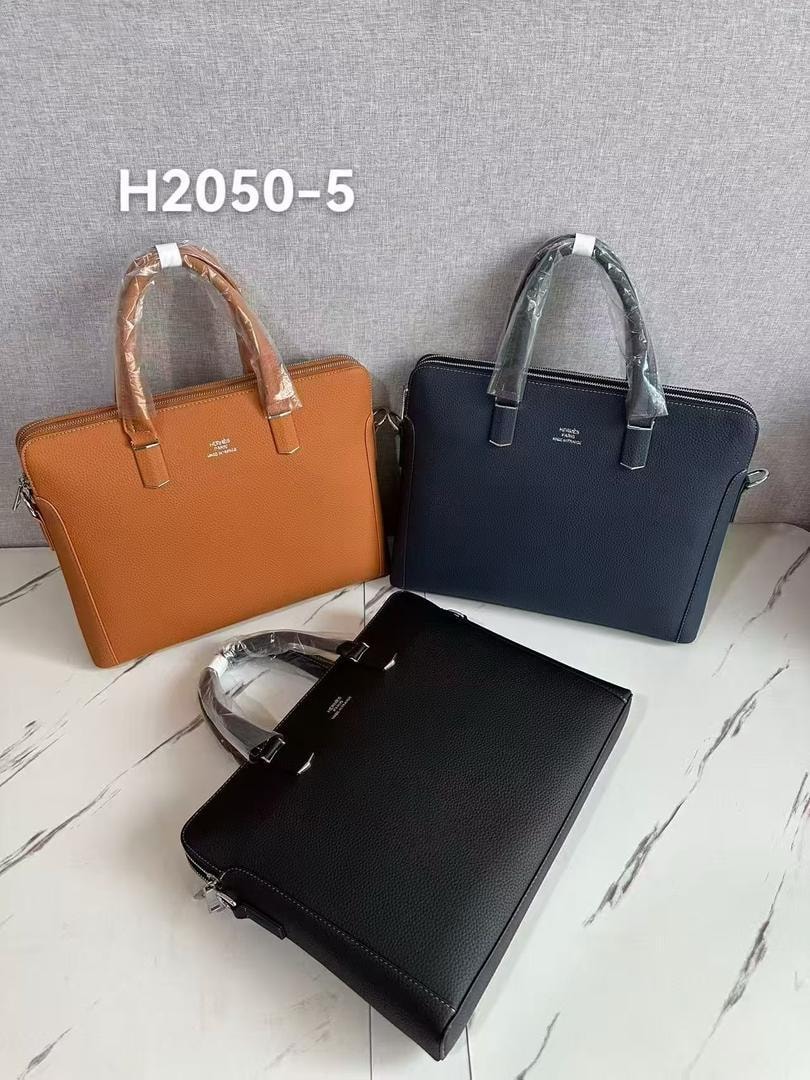 Three men's laptop bags displayed in orange, navy, and black colorways on a marble surface.