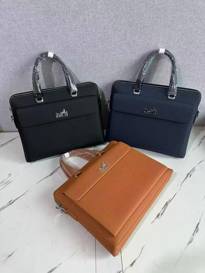 Three men's laptop bags in black, navy and brown displayed together on marble surface.