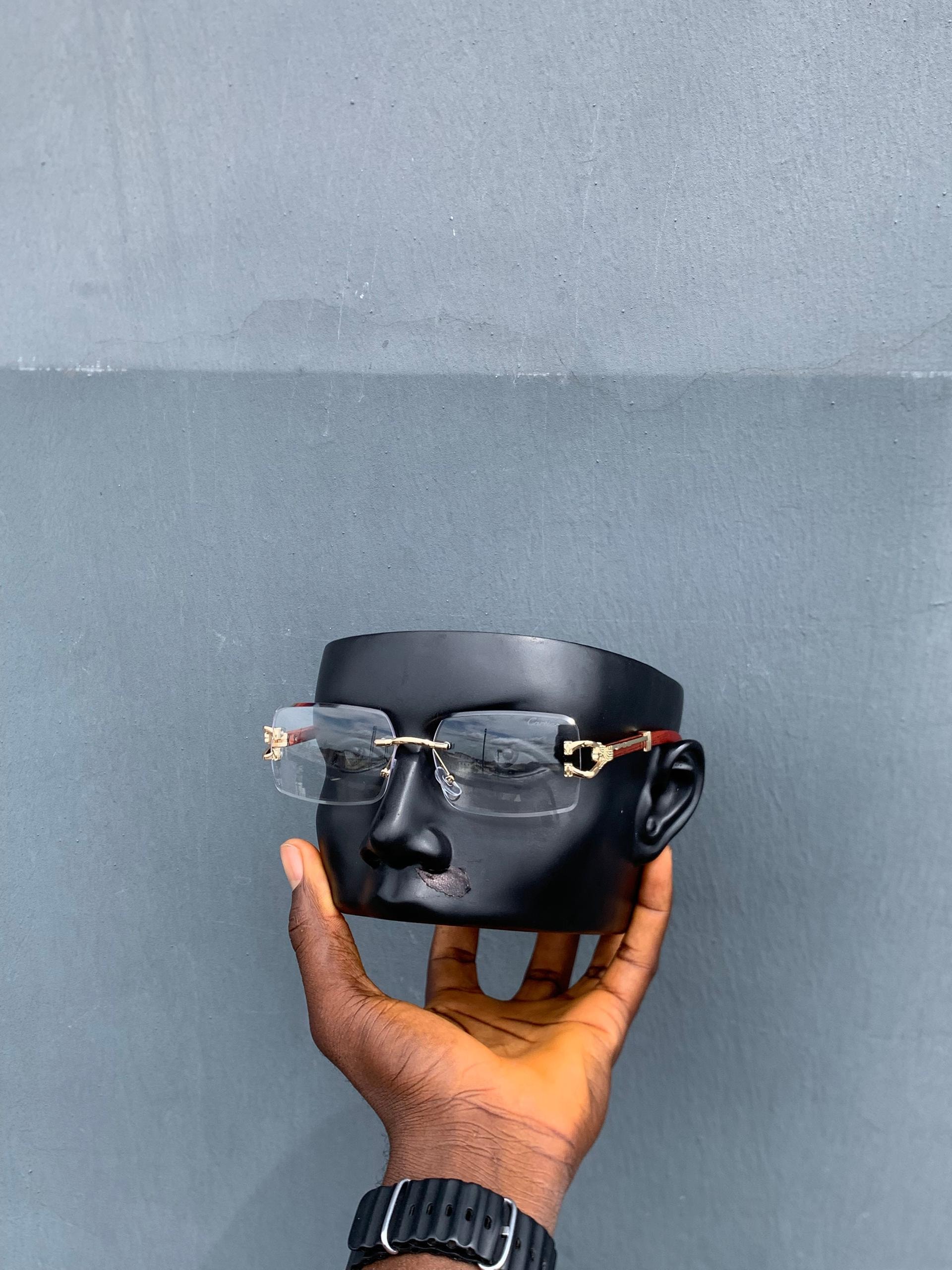 Cartier rimless rectangular sunglasses with clear lenses and red arm on mannequin.