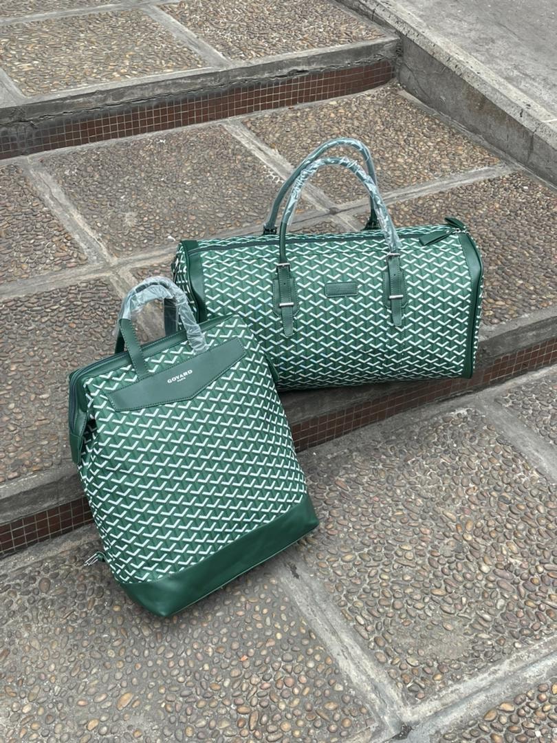 Green Goyard pattern backpack and duffel bag set on tiled steps.