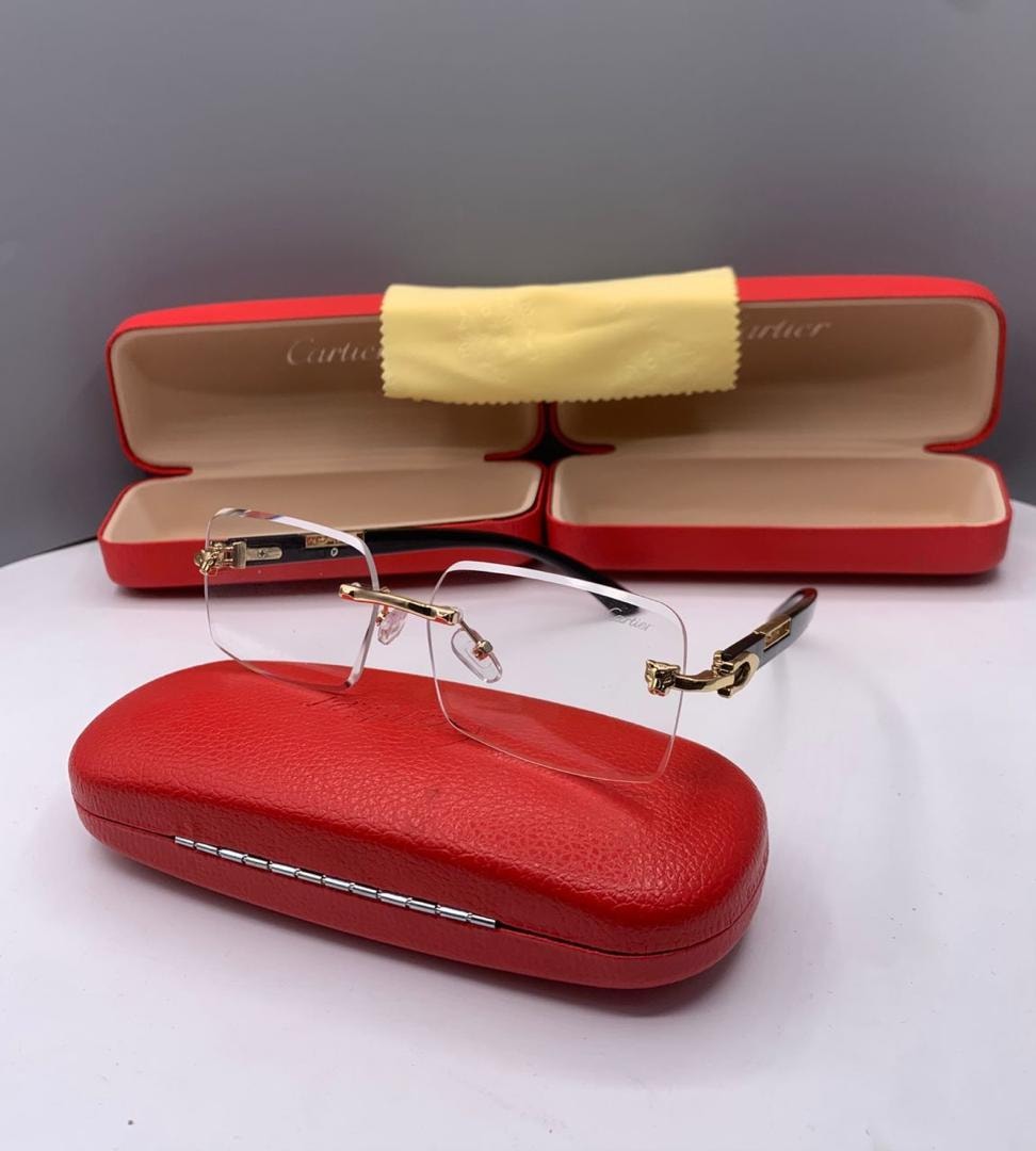Cartier rimless glasses with clear lenses and gold accents on red case.