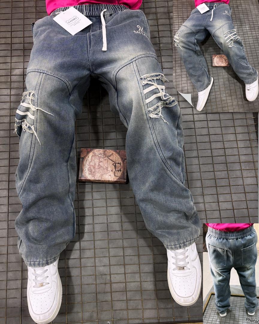 Model wearing blue denim joggers with ripped knees, lace details and white sneakers.