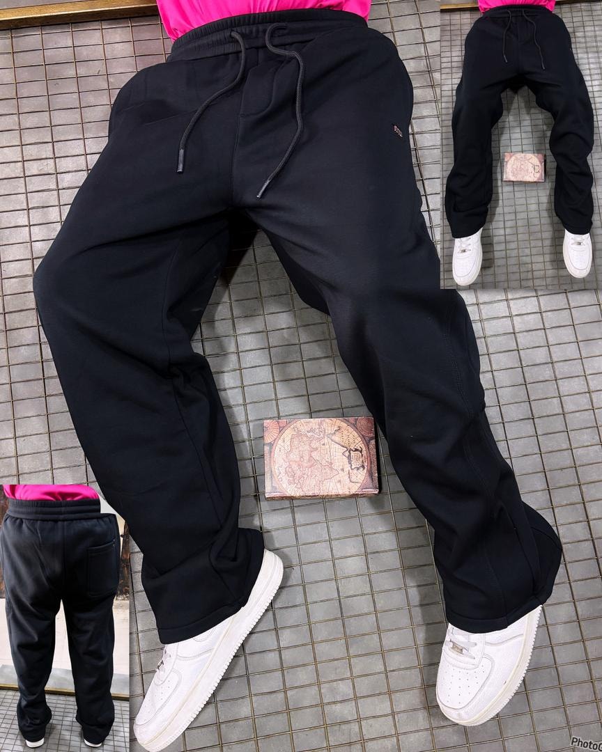 Side view of model in plain black denim joggers showing fit and small hip logo detail.