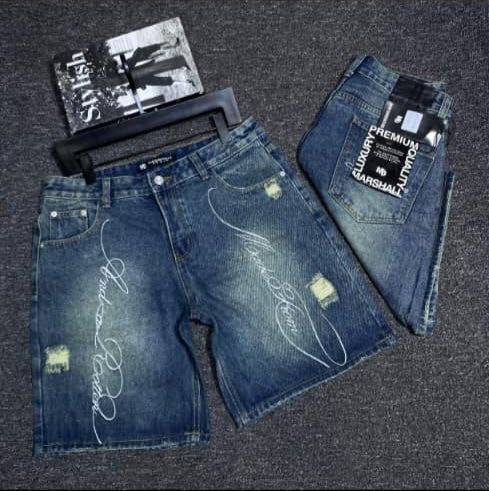 Blue denim shorts with white cursive script design, distressed patches and premium tags, front and back views.
