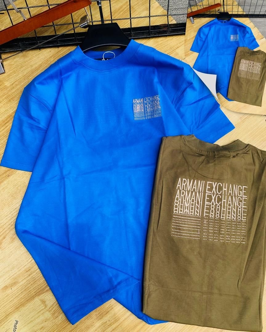 Blue and olive Armani Exchange printed t-shirts on wooden floor.