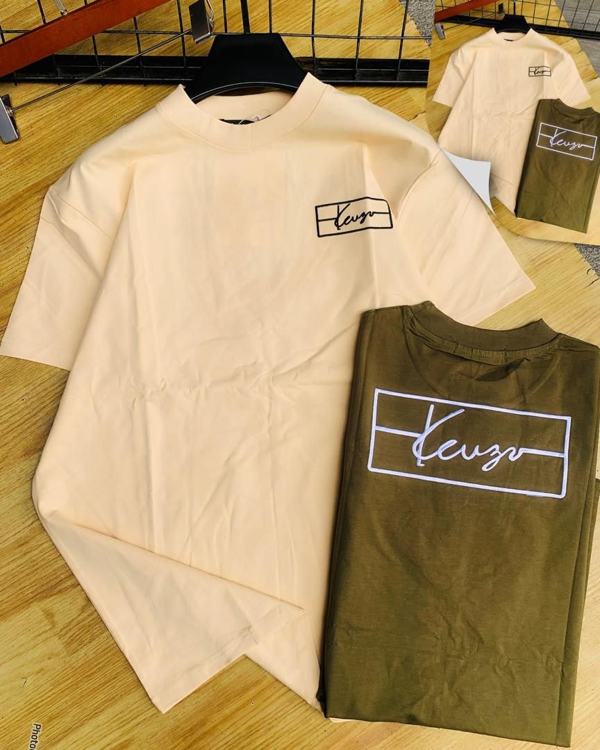 Beige and olive Keuzo logo t-shirts laid out on wooden surface.