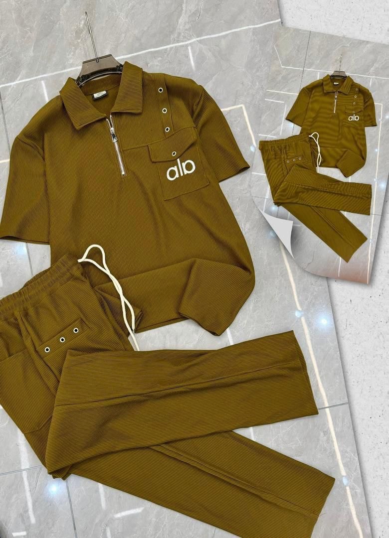 Olive Alo ribbed two-piece set with zip polo and pants on floor.