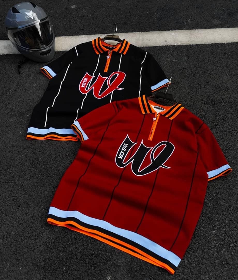 Red and black WILD striped zip polo shirts displayed outdoors with a helmet.