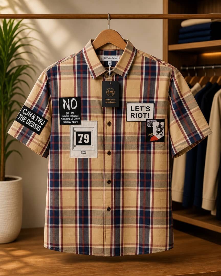 Beige plaid short sleeve collar shirt with graphic patches on hanger.