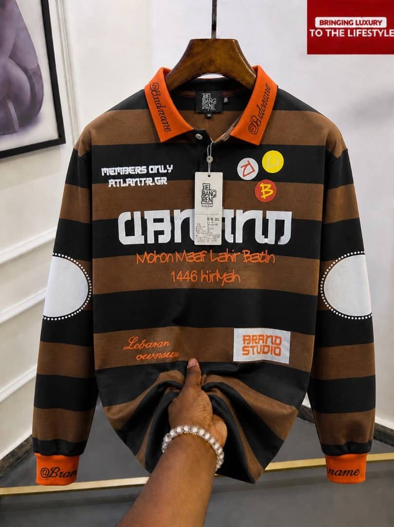 Brown and black striped long sleeve polo with orange collar and multiple graphic prints.