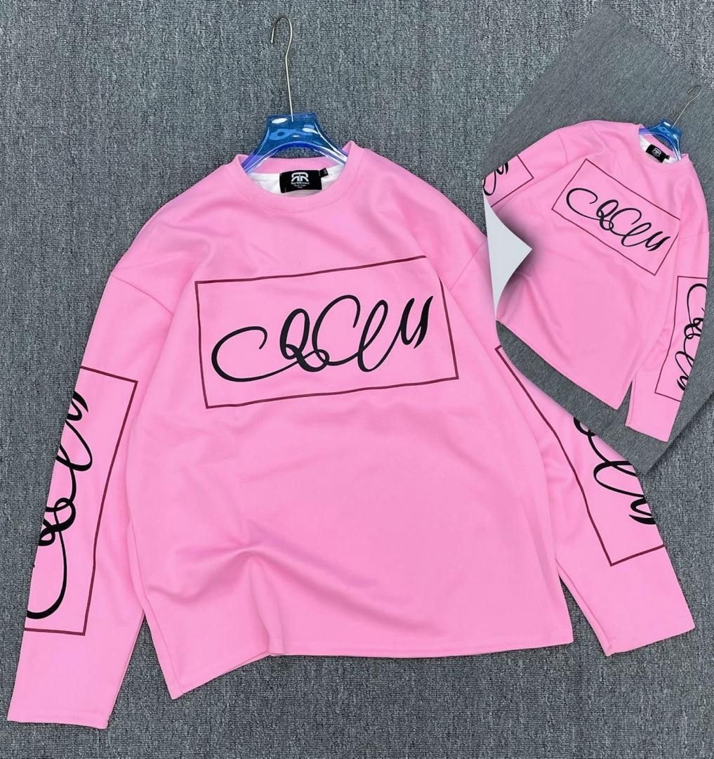 Pink long sleeve top with black cursive graphic print on chest and sleeves.