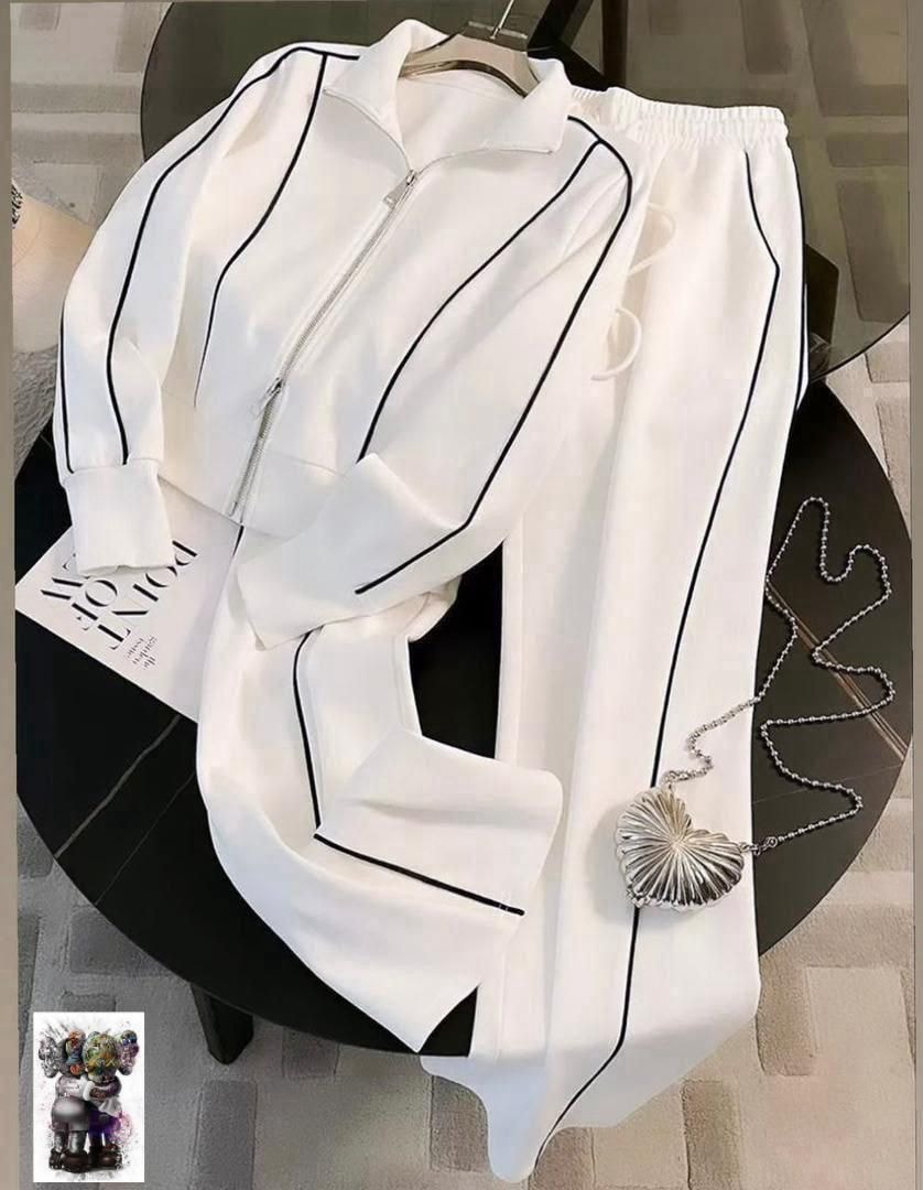 White zip-up jacket and pants with black piping laid flat on a table with accessories.