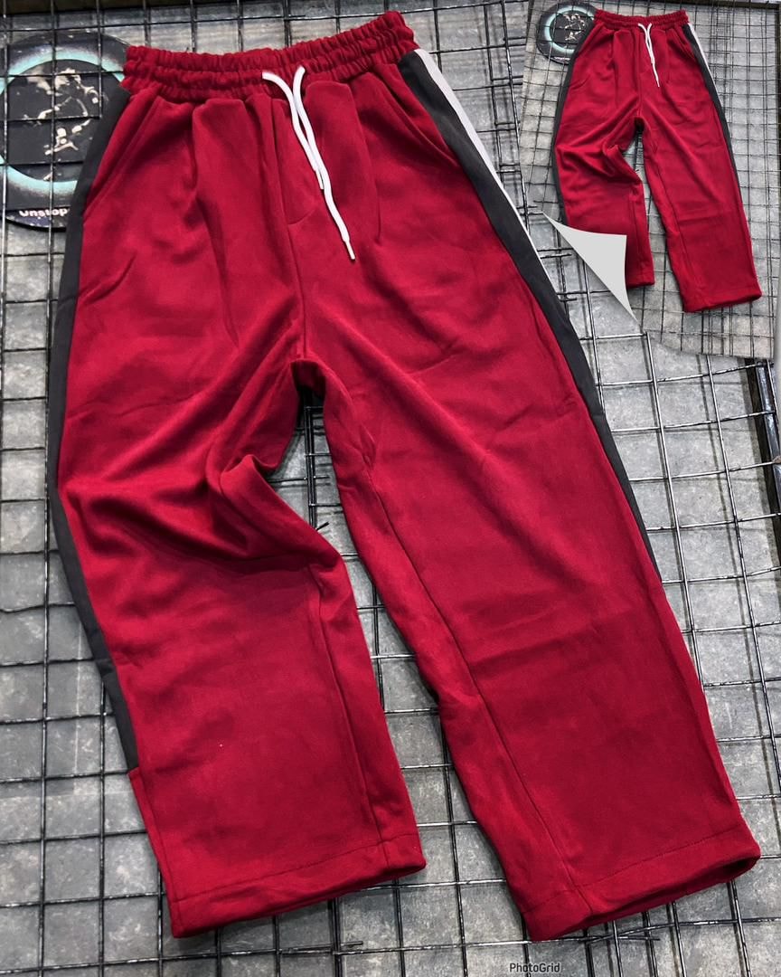 Red joggers with black and white side stripes shown flat on grid with inset full view.