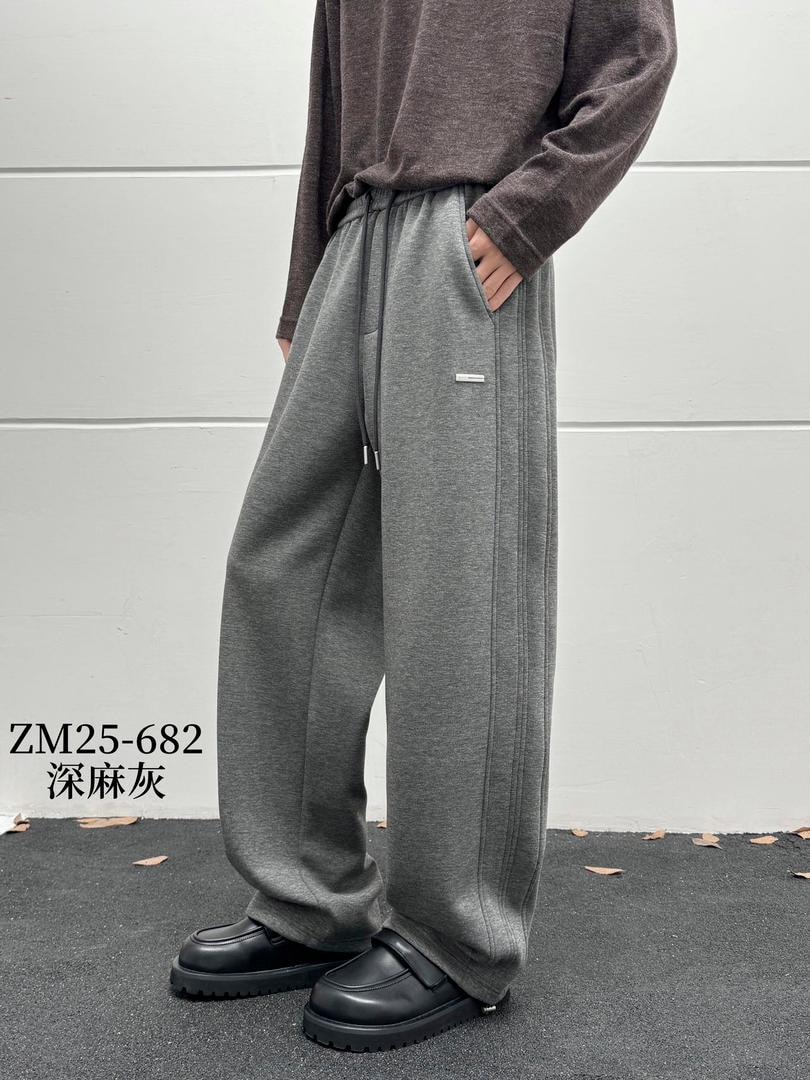 Model wearing gray relaxed fit joggers with drawstring waist, side pockets and logo detail.