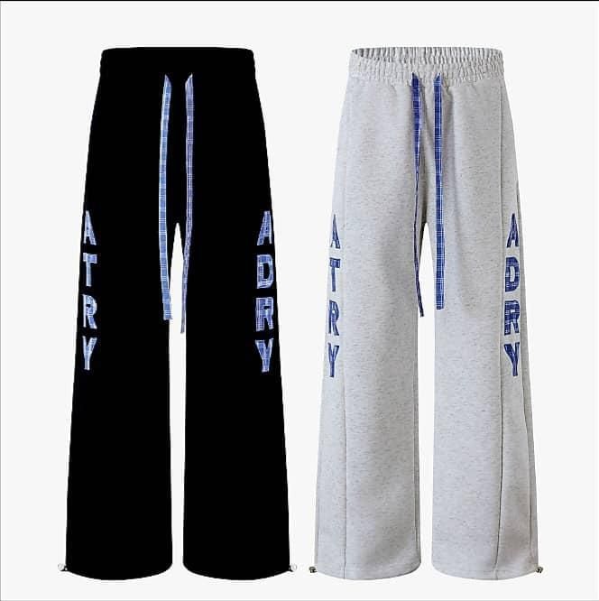 Black and gray wide leg joggers with vertical ADRY text and blue checkered drawstrings shown side by side.