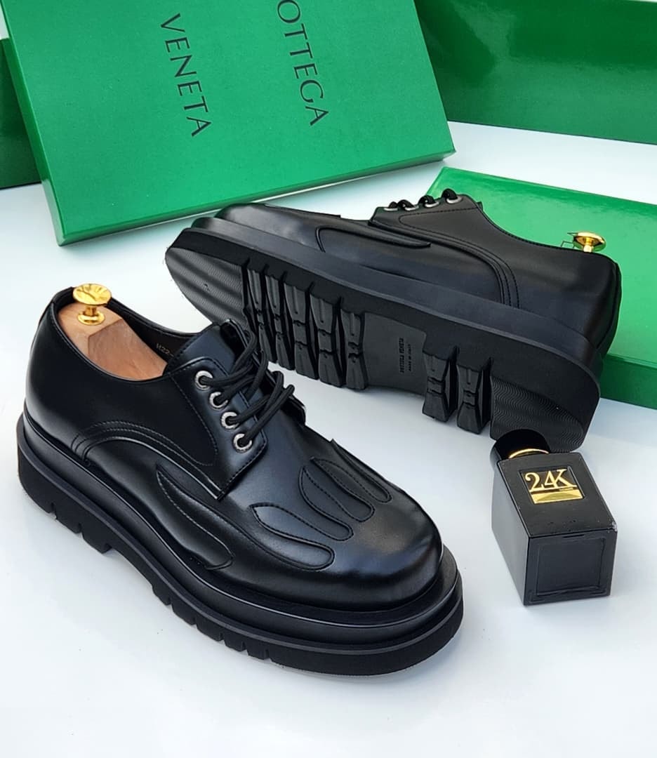 Black platform lace-up leather derby shoes with flame pattern toe detail, thick sole, and green Bottega Veneta box.